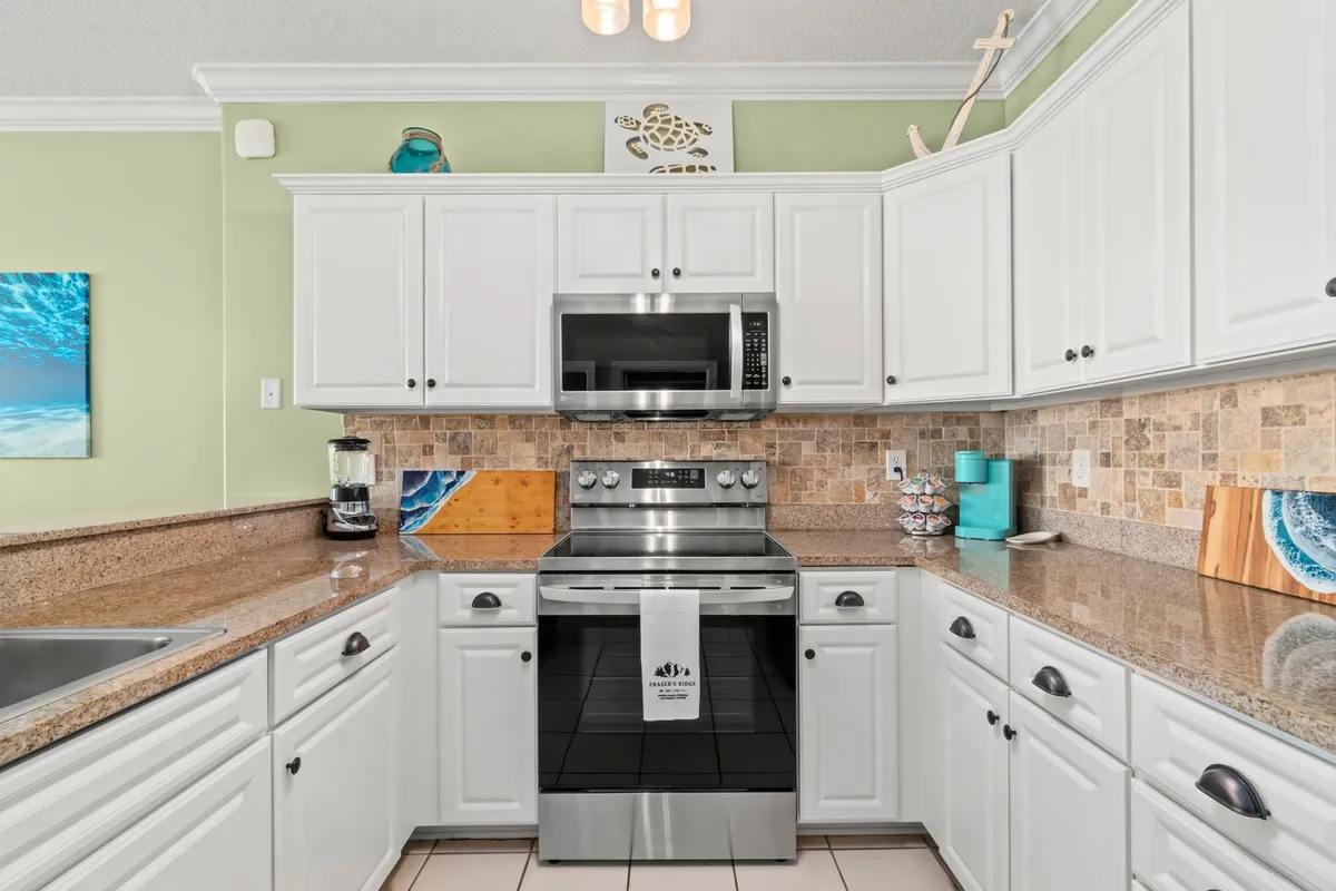 A modern kitchen with sleek stainless steel appliances, granite countertops, and tasteful decorative art pieces. The layout is both functional and stylish, featuring complete cookware and ample workspace, ideal for preparing meals or enjoying a morning coffee.
